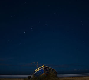 Ferris wheel by sea against sky at night