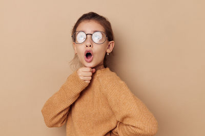 Portrait of young woman wearing sunglasses against pink background