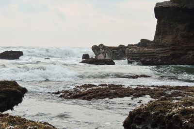 Scenic view of sea by cliff against sky