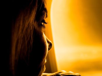 Close-up of woman looking at airplane window during sunset