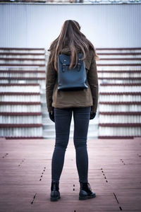 Rear view of woman standing against wall