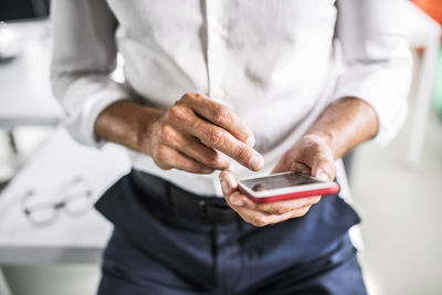 Close-up of businessman using cell phone in office