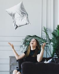 Portrait of young woman sitting against wall