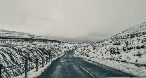 Road leading towards snow covered mountain against sky