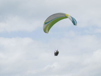 Low angle view of person paragliding against sky