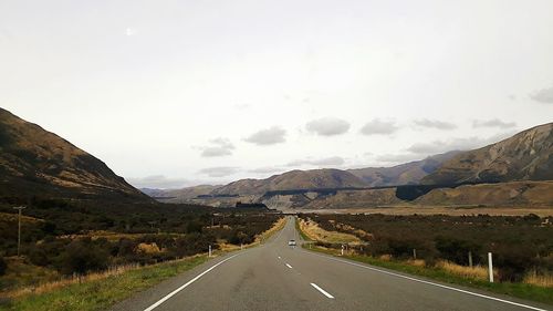 Road leading towards mountains against sky