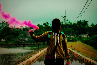Man wearing hooded shirt while holding pink distress flare
