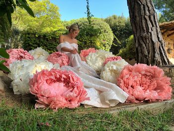 Woman with pink flowers on grass against trees