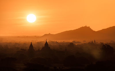 Silhouette of temple against mountain during sunset