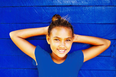 Portrait of a smiling girl against blue wall