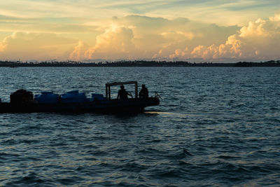 Silhouette boat in sea against sky during sunset