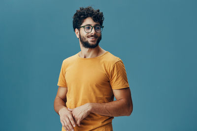 Portrait of young man standing against blue background