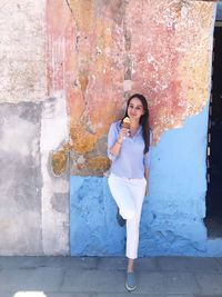 Portrait of woman standing against wall