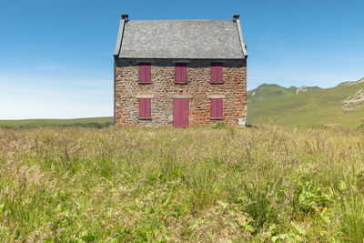 House with red shutters in the middle of nature in the sancy massif in france