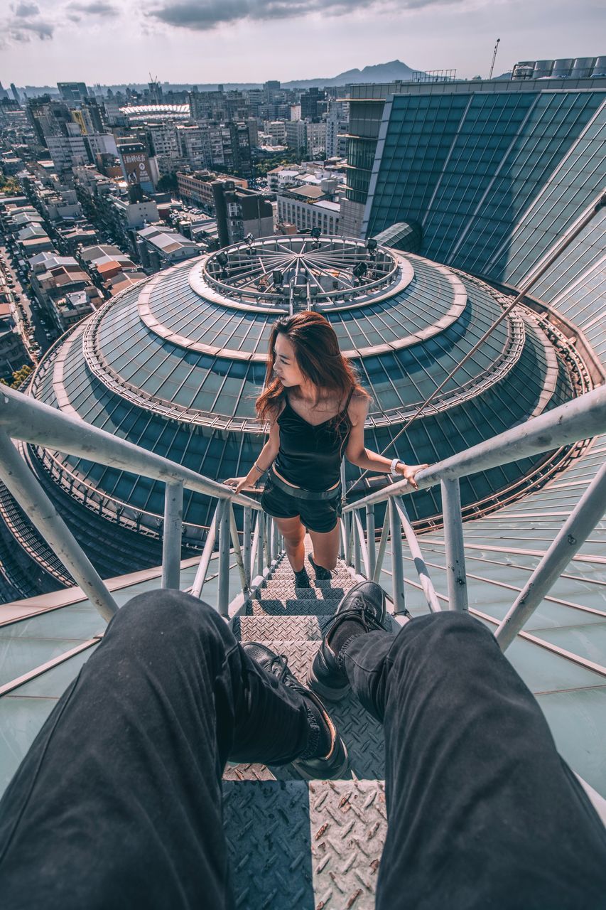 sitting, high angle view, casual clothing, full length, one person, built structure, architecture, day, technology, real people, wireless technology, outdoors, adult, people