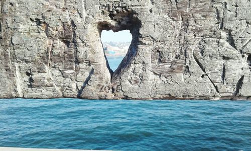 Rock formation in sea against sky