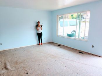 Teenage girl standing against blue wall at home
