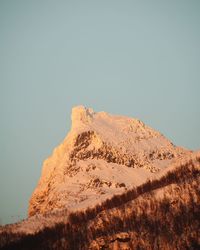 Low angle view of snowcapped mountain against clear sky