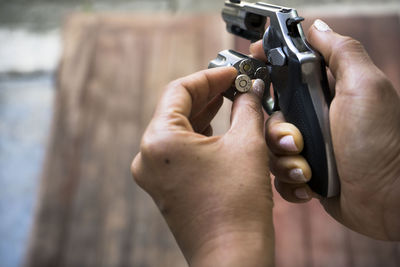 Cropped hands of woman inserting bullets in handgun
