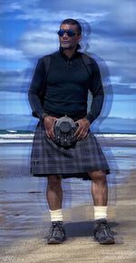 Man wearing sunglasses standing at beach against sky