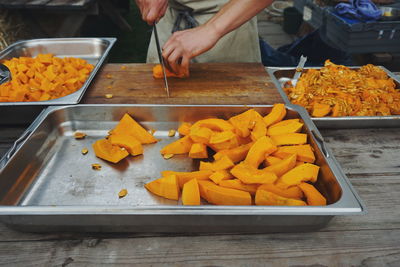 Midsection of chef cutting pumpkin on table