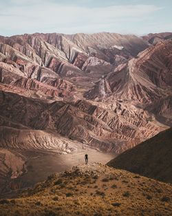 Man on cliff against mountain range