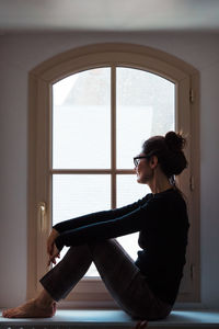 Woman looking through window at home