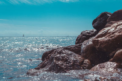 Rock formations on shore against blue sky
