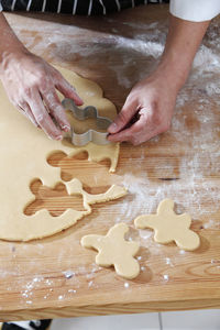 Cropped hands of chef cutting dough with pastry cutter at table