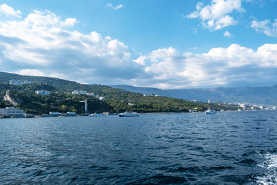 Scenic view of sea by mountain against sky