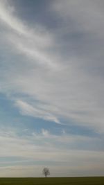 Scenic view of grassy field against cloudy sky