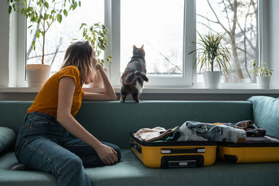 Side view of woman with dog sitting on sofa at home