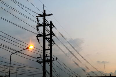 Low angle view of silhouette electricity pylon against sky during sunset