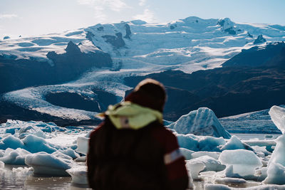 Rear view of woman standing on snowcapped mountain