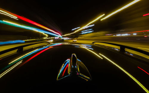 Cropped image of car with light trails on road at night