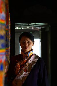 Portrait of smiling young woman standing against wall