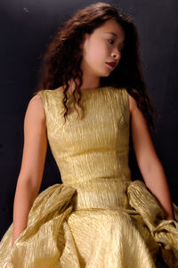 Woman in dress sitting against black background