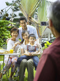 Cropped image of senior man photographing family at back yard