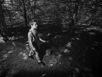High angle view of boy walking on field at forest