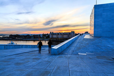 Rear view of man and woman against sky during sunset