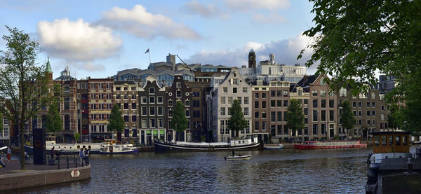 Boats in river in city against sky