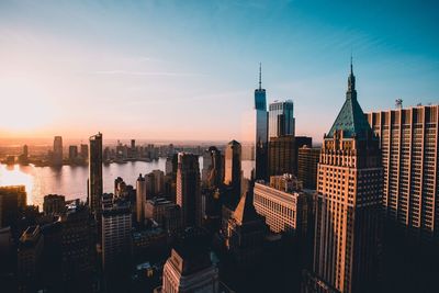 Modern buildings in city against sky during sunset