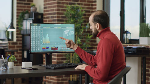 Businessman analyzing graph on desktop pc at office