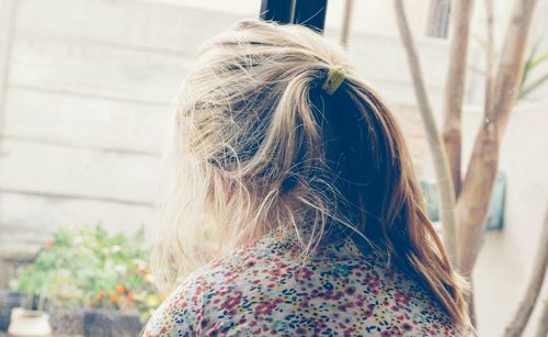 Close-up rear view of girl with messy hair by window at home