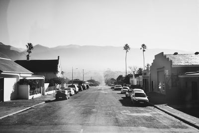 Cars on road by buildings against sky in city