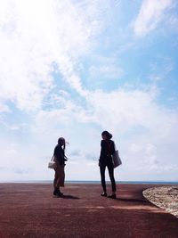 Side view of couple standing on road against sky