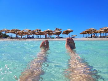 People swimming in pool against clear blue sky