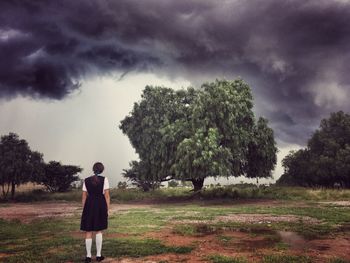 Rear view of man standing on field against sky