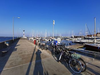 Boats moored at harbor against clear blue sky