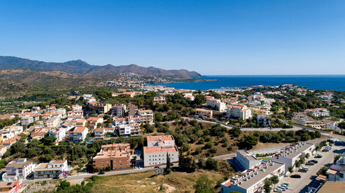 High angle view of townscape by sea against clear blue sky